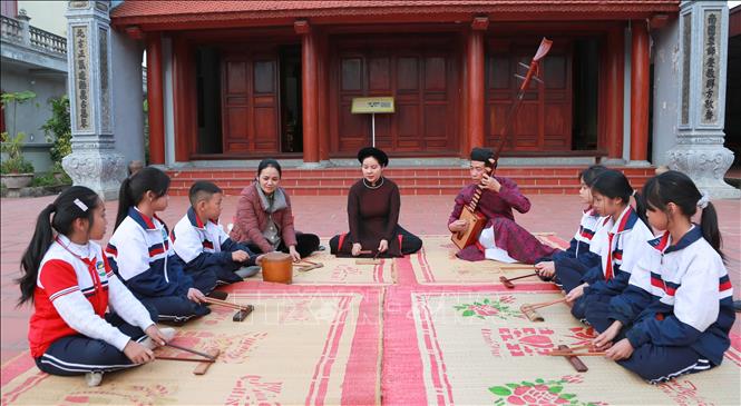 Học sinh Trường Tiểu học Hòa Bình học ca trù cùng các ca nương, kép đàn của Câu lạc bộ Ca trù Đông Môn. Ảnh: Minh Thu - TTXVN