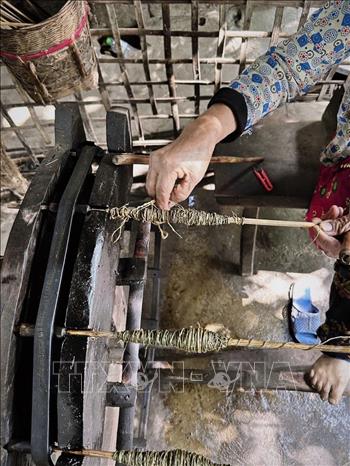 Sợi vải được căng và buộc trên khung để tạo hoa văn kháng màu. Ảnh: Phương Anh - TTXVN phát