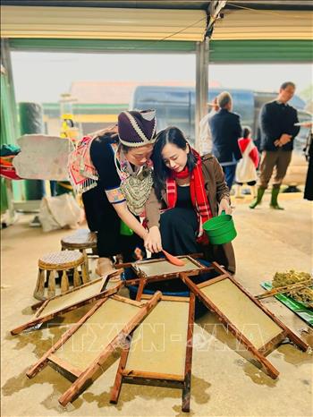 Du khách trải nghiệm làm giấy Dó của đồng bào người Mông. Ảnh: TTXVN phát