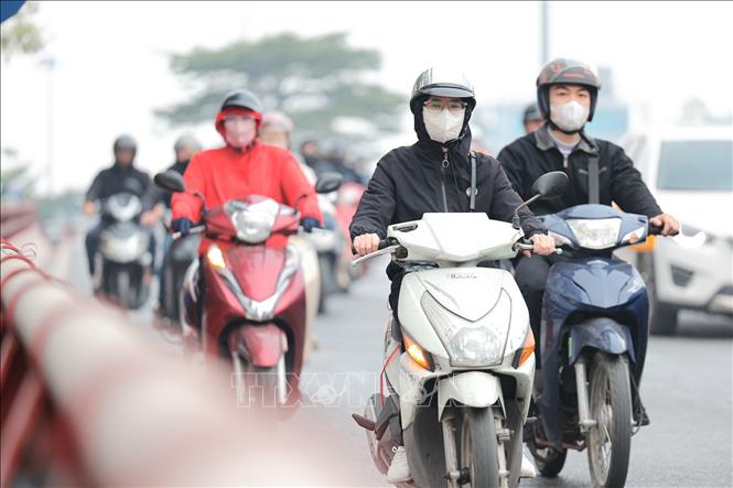 Người bịt khẩu trang để hạn chế hít phải bụi mịn, không khí ô nhiễm. Ảnh: Lê Đông - TTXVN