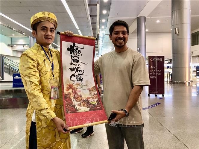 Du khách hào hứng khoe chữ thư pháp được tặng tại sự kiện. Ảnh: Mỹ Phương - TTXVN.