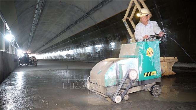 Công nhân thi công hạng mục tạo độ nhám cho mặt đường bên trong hầm. Ảnh: Hữu Quyết - TTXVN