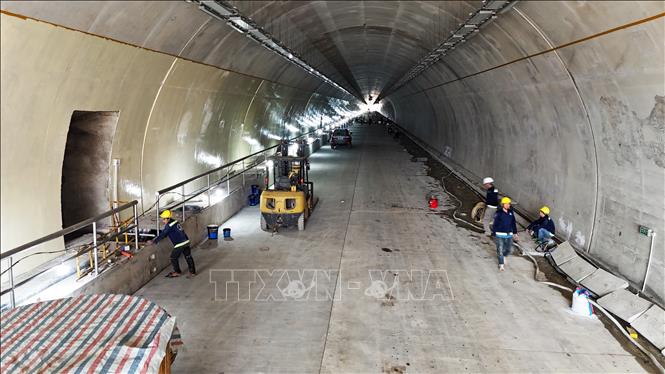Công nhân và các phương tiện, máy móc thi công các hạng mục bên trong ống hầm. Ảnh: Hữu Quyết - TTXVN