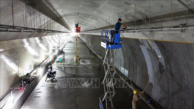 Công nhân và các phương tiện, máy móc thi công các hạng mục kỹ thuật cuối cùng bên trong ống hầm. Ảnh: Hữu Quyết - TTXVN