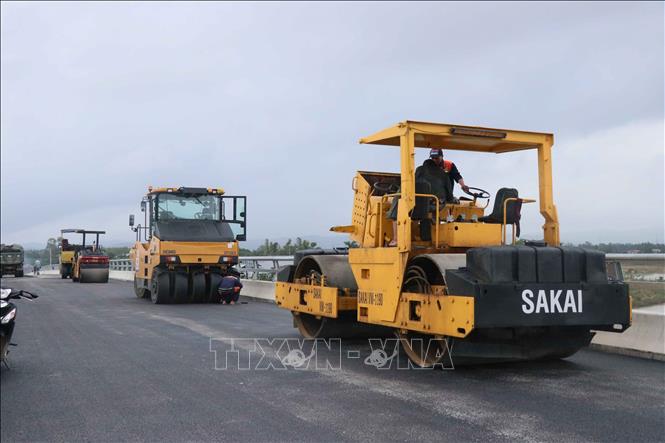 Một mũi thi công hoàn thiện lớp thảm bê tông nhựa cuối cùng và lắp đặt khe co giản trên mặt cầu. Ảnh: Đoàn Hữu Trung - TTXVN