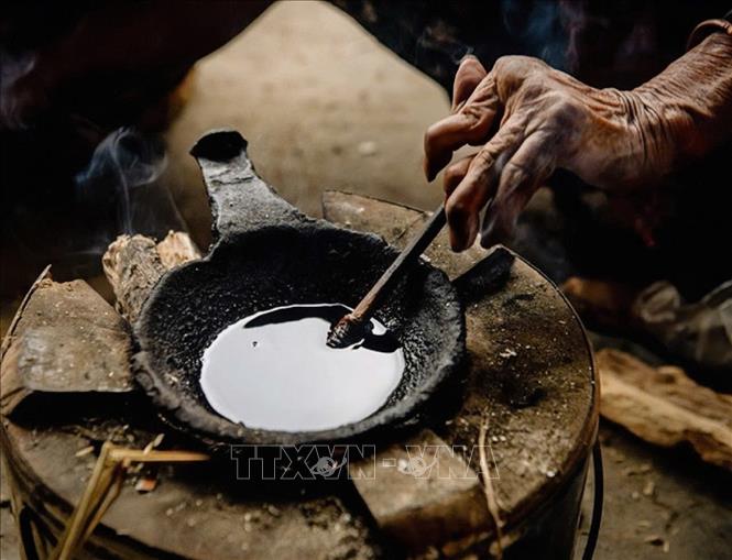 Beeswax is melted to draw the traditional patterns of Mong people on linen fabric. VNA Photo: Phương Anh/Photo by courtesy