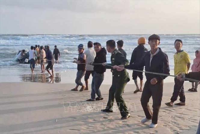 Các lực lượng chức năng và người dân triển khai kéo ghe vào bờ. Ảnh: TTXVN phát