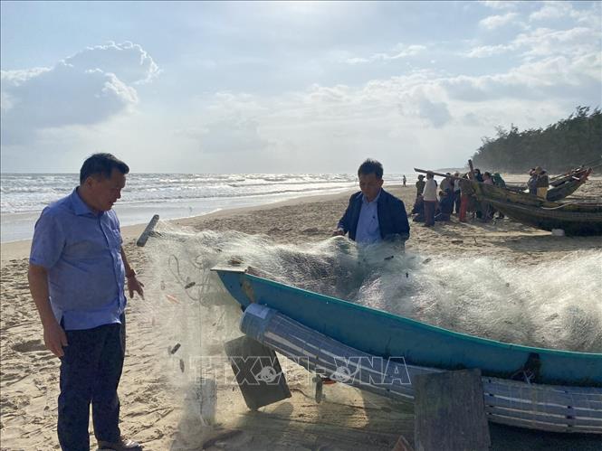 Chiếc ghe đánh cá của nạn nhân được các lực lượng chức năng và người dân kéo lên bờ. Ảnh: TTXVN phát