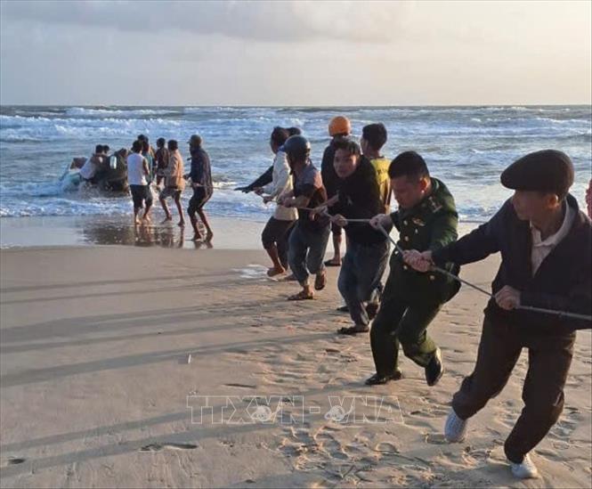 Các lực lượng chức năng và người dân triển khai kéo ghe vào bờ. Ảnh: TTXVN phát