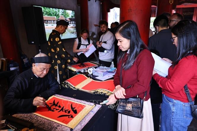 Du khách Thủ đô và nước ngoài tham quan, tìm hiểu nét đẹp xin chữ và cho chữ tại di tích Văn Miếu – Quốc Tử Giám trong dịp nghỉ lễ. Ảnh: Minh Đức – TTXVN