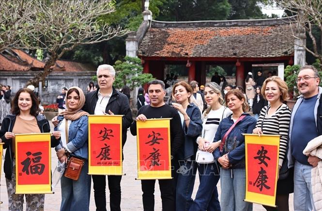 Du khách Thủ đô và nước ngoài tham quan, tìm hiểu nét đẹp xin chữ và cho chữ tại di tích Văn Miếu – Quốc Tử Giám trong dịp nghỉ lễ. Ảnh: Minh Đức – TTXVN