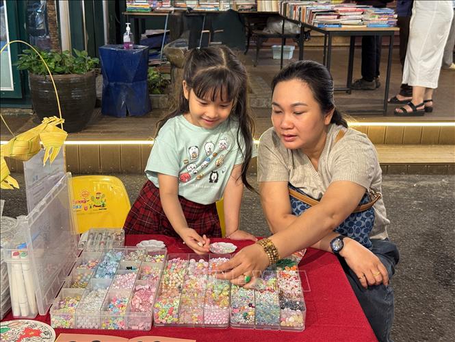 Phụ huynh đưa em nhỏ tới Ngày hội để tham gia workshop làm vòng tay. Ảnh: Thu Hương - TTXVN