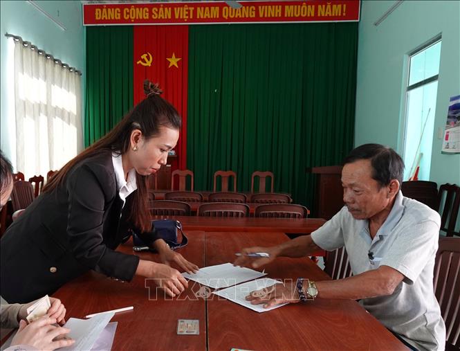 Cán bộ phòng văn hóa xã Thuận Nam chi trả quà 418 của Chính phủ cho thân nhân gia đình người có công với cách mạng ở thôn Nho Lâm. Ảnh: Công Thử - TTXVN