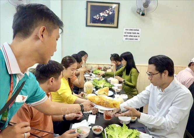 Du khách thưởng thức ẩm thực địa phương đặc trưng trong tour du lịch Thành phố Hồ Chí Minh. Ảnh: Mỹ Phương – TTXVN