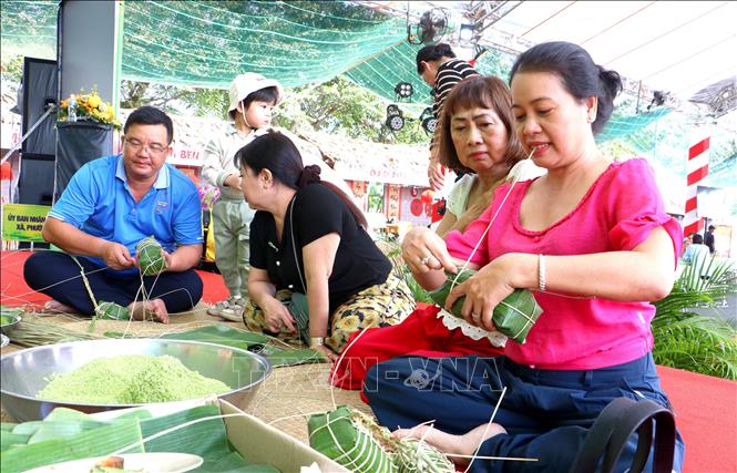 Khách tham quan cùng người dân địa phương tham gia hoạt động gói bánh tét truyền thống. Ảnh: Lê Thúy Hằng – TTXVN