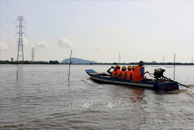Công nhân Công ty Truyền tải Điện 4 (Tập đoàn Điện lực Việt Nam) kiểm tra an toàn đường dây 220kV Châu Đốc-Takeo trong mùa lũ, đảm bảo điện cung cấp cho Campuchia. Ảnh: Ngọc Hà - TTXVN