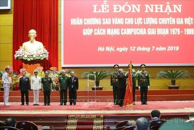 Thường trực Ban Bí thư Trần Quốc Vượng gắn Huân chương Sao vàng của Chủ tịch nước lên Cờ truyền thống của Lực lượng chuyên gia Việt Nam giúp Cách mạng Campuchia. Ảnh: Dương Giang -TTXVN