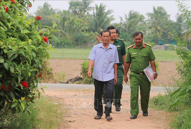 Các thành viên trong Đội dân phòng cùng Bộ đội Biên phòng và Công an phường Hà Tiên xuống nhà dân ở khu phố Xà Xía tuyên truyền, cảnh báo người dân về các thủ đoạn lừa đảo trên không gian mạng. Ảnh: Công Mạo-TTXVN 