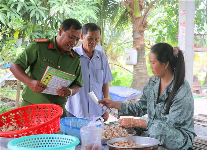 Các thành viên trong Đội dân phòng cùng Bộ đội Biên phòng và Công an phường Hà Tiên đến gia đình chị Nèang Đưa (khu phố Xà Xía) tuyên truyền, cảnh báo người dân về các thủ đoạn lừa đảo trên không gian mạng. Ảnh: Công Mạo-TTXVN 