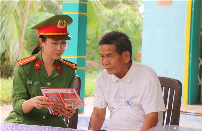 Trung tá Ngô Kim Thảo, Phó Trưởng Công an phường Hà Tiên (tỉnh An Giang) xuống nhà dân cùng với các thành viên Đội dân phòng tuyên truyền, cảnh báo người dân về các thủ đoạn lừa đảo trên không gian mạng. Ảnh: Công Mạo-TTXVN 