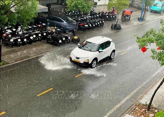 Ô tô lưu thông trong cơn mưa trái mùa chiều 6/1/2026 trên đường Kênh Tân Hóa, phường Tân Phú. Ảnh: Hồng Đạt - TTXVN 
