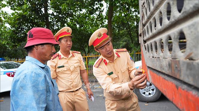 CSGT Tây Ninh dán phản quang cảnh báo cho phương tiện chở mía nguyên liệu, góp phần đảm bảo an toàn giao thông. Ảnh: Minh Phú - TTXVN