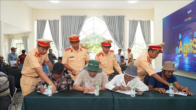 CSGT Tây Ninh hướng dẫn lái xe chở mía kí cam kết chấp hành nghiêm Luật Giao thông đường bộ. Ảnh: Minh Phú – TTXVN