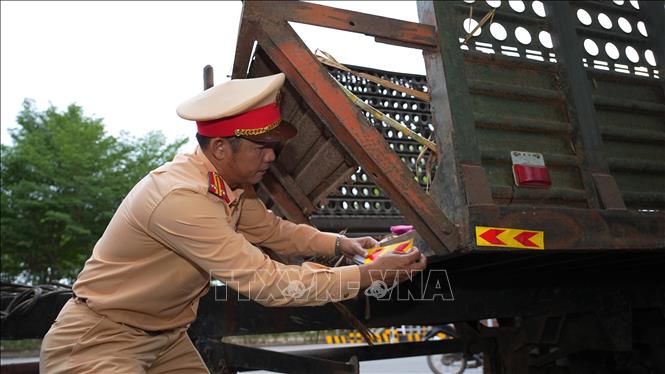CSGT Tây Ninh dán phản quang cảnh báo cho phương tiện chở mía nguyên liệu, góp phần đảm bảo an toàn giao thông. Ảnh: Minh Phú - TTXVN