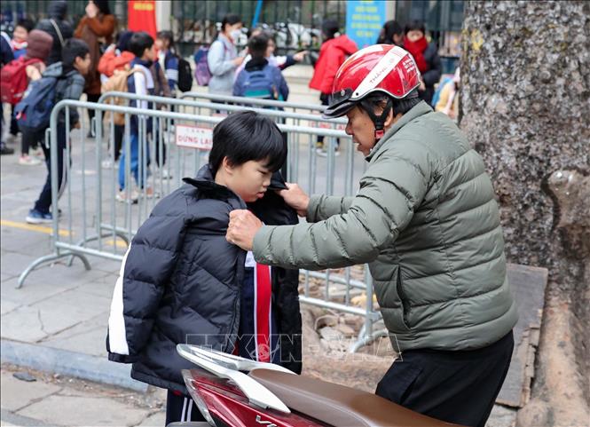 Trẻ em được giữ ấm khi lưu thông bằng xe máy. Ảnh: Vũ Quang - TTXVN
