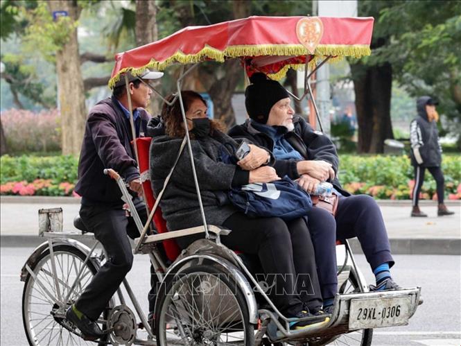 Khách du lịch nước ngoài mang áo khoác dày khi đi xích lô ngắm cảnh Hà Nội. Ảnh: Vũ Quang - TTXVN
