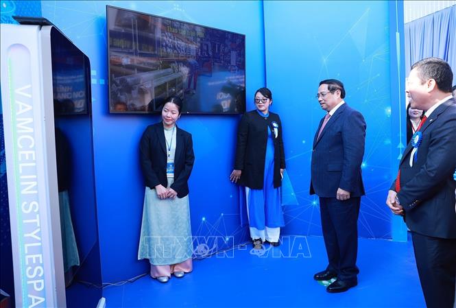 Thủ tướng Phạm Minh Chính thử ứng dụng may đo tự động áp dụng tại xưởng may của Tổng Công ty May 10. Ảnh: Dương Giang-TTXVN
