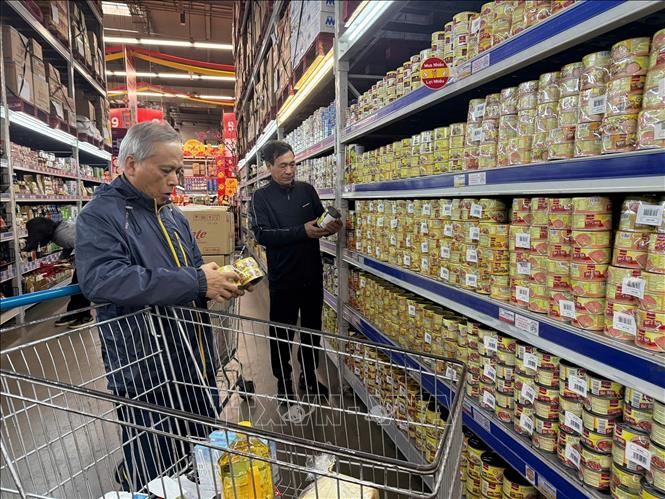  Người dân kiểm tra đồ hộp kỹ trước khi mua. Ảnh Tiến Vĩnh  - TTXVN 