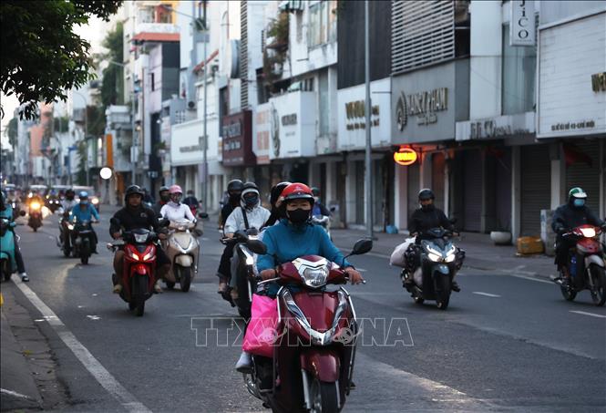 Người dân trong trang phục giữ ấm đi làm trên đường Hồ Văn Huê (phường Đức Nhuận) thời điểm 6 giờ 20 phút sáng 9/1/2026. Ảnh: Hồng Đạt - TTXVN 

