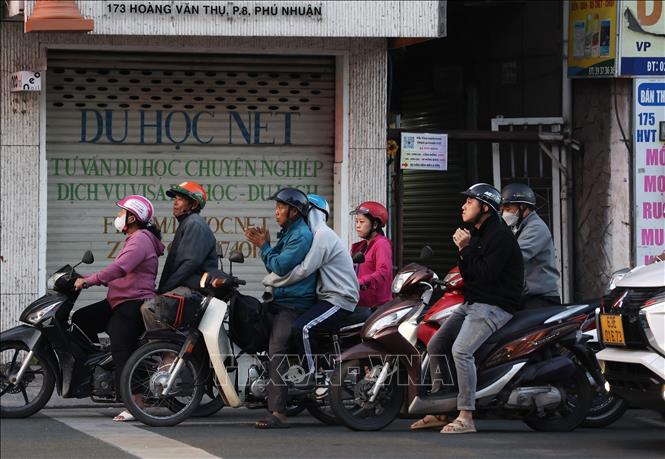 Người dân Thành phố Hồ Chí Minh trong cái lạnh với nhiệt độ 17 độ C, xuống thấp nhất trog 10 năm qua.
Ảnh: Hồng Đạt - TTXVN 
