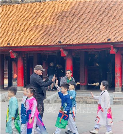 Khách du lịch quốc tế giao lưu thân thiện với các em học sinh. Ảnh: Tuyết Mai - TTXVN