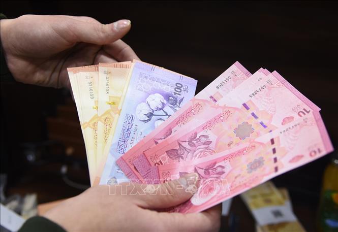 Ngân hàng Trung ương Syria cho biết sau nhiều tháng chuẩn bị, việc đổi tiền Syria cũ lấy tiền giấy mới (ảnh) chính thức bắt đầu vào sáng 3/1/2026. Theo sắc lệnh, tờ tiền cũ sẽ bị loại bỏ đi hai chữ số 0, có nghĩa là cứ 100 bảng Syria cũ sẽ tương đương với 1 bảng Syria mới. Việc phát hành đồng tiền mới được xem là bước đi quan trọng trong quá trình tái lập ổn định tài chính và khôi phục niềm tin vào hệ thống kinh tế của Syria. Ảnh: THX/TTXVN