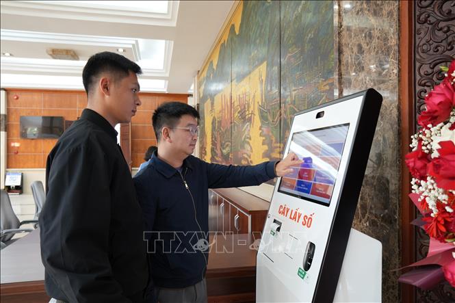 Cán bộ trung tâm hướng dẫn lấy số thứ tự cho người dân. Ảnh Tiến Vĩnh  - TTXVN 