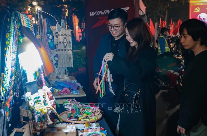 Du khách tìm hiểu các sản phẩm thủ công độc đáo tại khu vực Hồ Hoàn Kiếm tối 10/1. Ảnh: Hoàng Hiếu - TTXVN