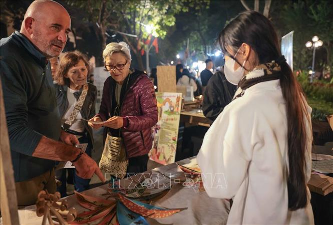 Foreign visitors are interested in handicraft products displayed at Hoan Kiem Lake area. VNA Photo