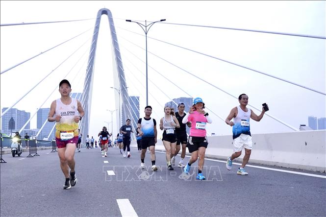 Các vận động viên hai cự ly 21km và 42km đang cùng di chuyển trên Cầu Ba Son, tiến về đích. Ảnh: Trung Tuyến - TTXVN 