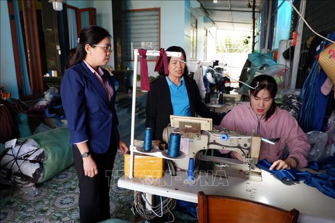 Chủ tịch Hội Liên hiệp Phụ nữ xã Long Cang - chị Hoàng Uyên (bìa trái) thăm tổ hợp may có vay vốn Ngân hàng Chính sách xã hội của chị Lê Thị Giang. Ảnh: Đức Hạnh - TTXVN 