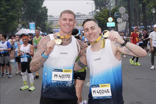 Two runners, Victorbailey (Denmark) and Aless Mac (Italy), with their prizes after completing the 42km race. VNA Photo: Trung Tuyến