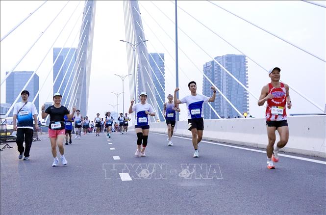 Runners in the 21km and 42km races are moving together on Ba Son Bridge, heading towards the finish line. VNA Photo: Trung Tuyến