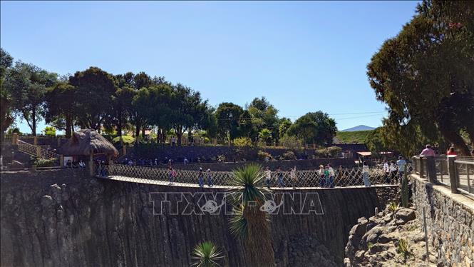 Khách du lịch băng qua cây cầu treo bắc ngang hẻm núi, một trong những điểm tham quan thu hút tại Prismas Basálticos, cho phép du khách tiếp cận gần hơn với các khối đá bazan độc đáo. Ảnh: Phi Hùng-PV TTXVN tại Mexico