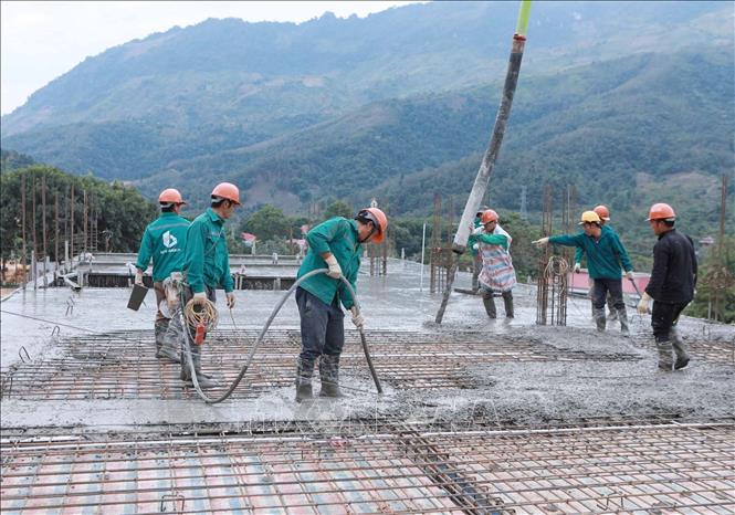 Đơn vị thi công dùng thiết bị máy móc hiện đại để bơm bê tông đổ mái, kết hợp đầm góp phần đảm bảo kết cấu chất lượng công trình. Ảnh: Quý Trung – TTXVN