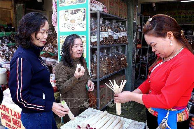 Chủ cửa hàng hướng dẫn khách du lịch cách dùng cơm lam Mường Động. Ảnh: Thanh Hải - TTXVN