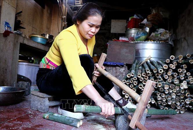 Công đoạn cắt ống tre, hóp hoặc nứa non để tạo vỏ nhồi gạo nếp làm cơm lam. Ảnh: Thanh Hải - TTXVN 