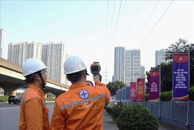 Công nhân EVNHANOI kiểm tra đường dây thông qua thiết bị bắn nhiệt. Ảnh: Quốc Lũy - TTXVN