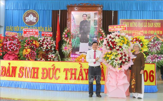 Đại diện Đảng ủy, HDND, UBND, Ủy ban MTTQ Việt Nam xã Phú Tân, tỉnh An Giang (trái) tặng hoa, chúc mừng lễ kỷ niệm 106 năm Ngày Đản sinh Đức Huỳnh Giáo chủ Phật giáo Hòa Hảo. Ảnh: Công Mạo-TTXVN