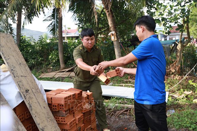 Công an tỉnh Khánh Hòa hỗ trợ người dân xã Diên Điền hỗ trợ khắc phục hậu quả lũ lụt. Ảnh: Đặng Tuấn - TTXVN